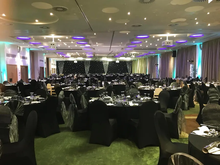 Black stretch chair covers with black and silver organza hoods at a gala dinner